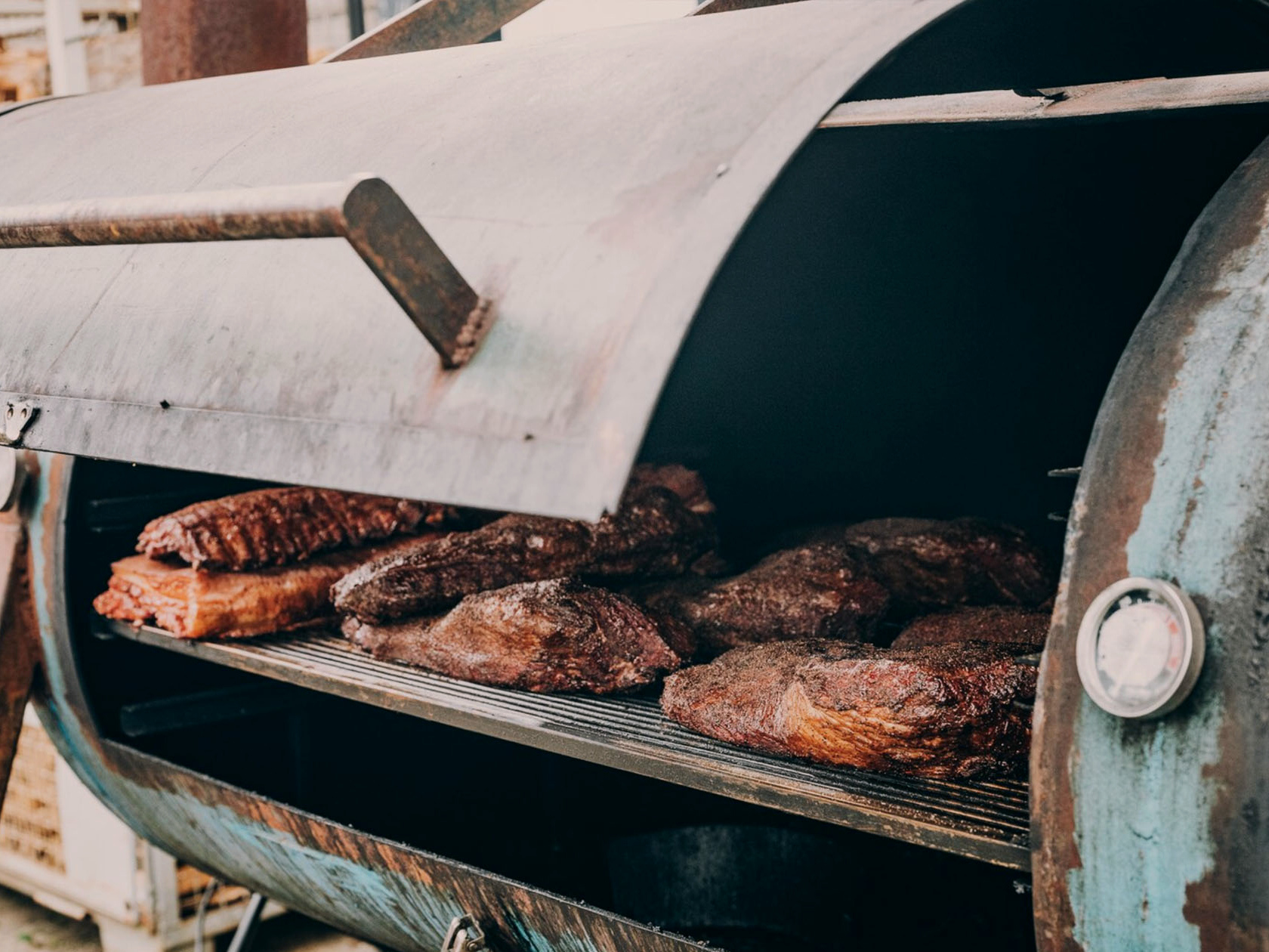Geöffneter Smoker mit mehreren Stücken Fleisch